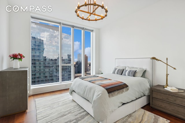 bedroom with a view of city, a notable chandelier, and wood finished floors