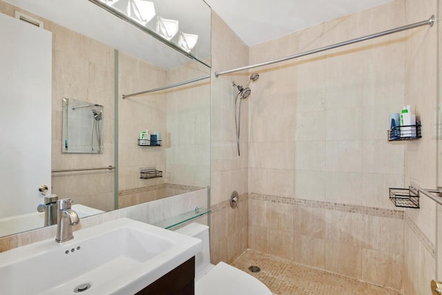 bathroom featuring toilet, vanity, and tiled shower