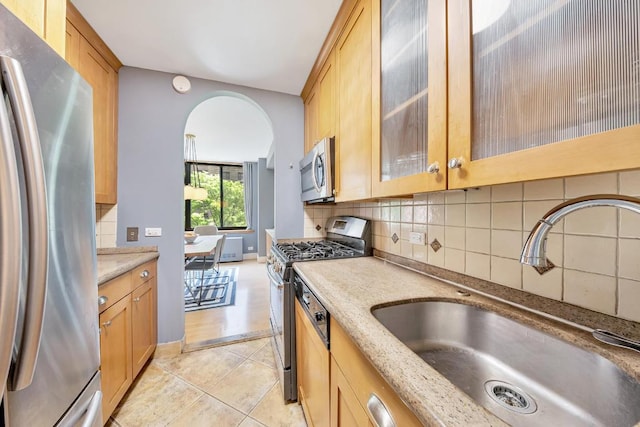 kitchen featuring sink, stainless steel appliances, tasteful backsplash, light stone counters, and light tile patterned flooring