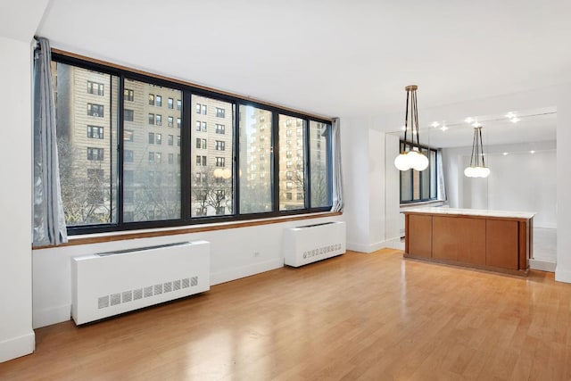 kitchen with radiator, light wood-type flooring, and decorative light fixtures