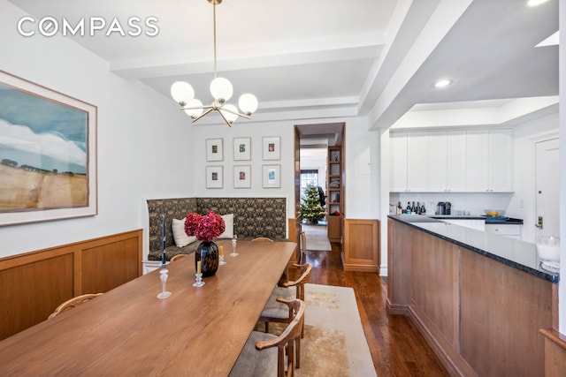 dining room featuring a chandelier, dark wood finished floors, and beamed ceiling