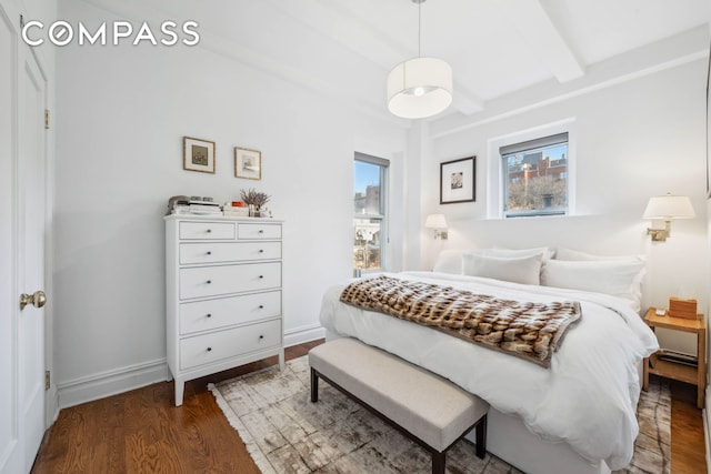 bedroom featuring beam ceiling, multiple windows, baseboards, and wood finished floors