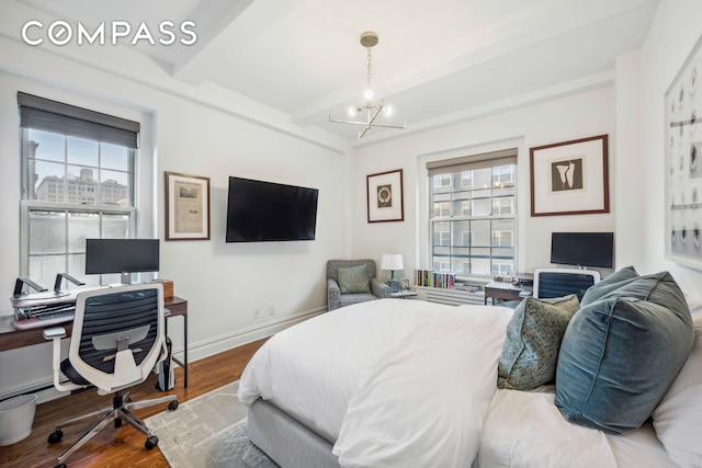 bedroom featuring multiple windows, baseboards, beam ceiling, and wood finished floors