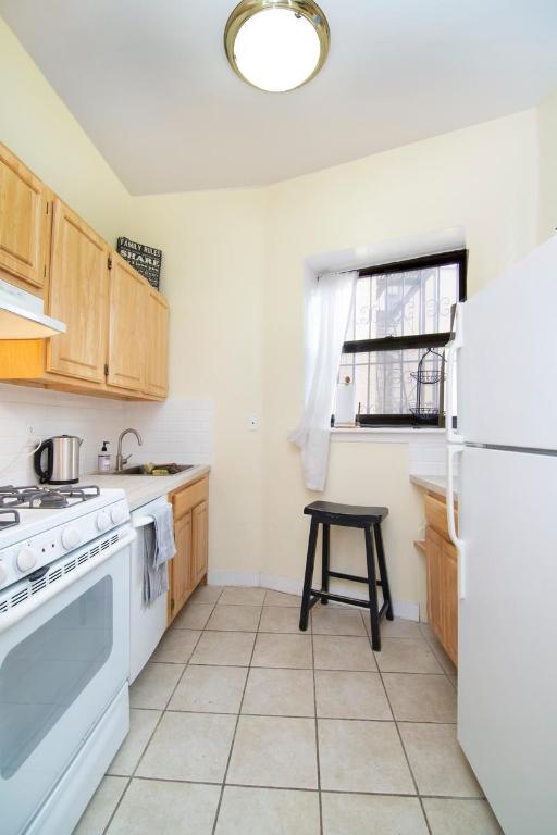 kitchen with light brown cabinetry, sink, white appliances, and light tile patterned floors