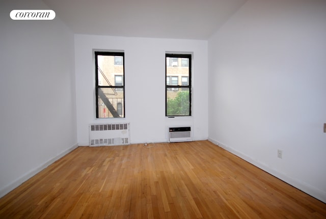 unfurnished room with heating unit, radiator heating unit, and light wood-type flooring