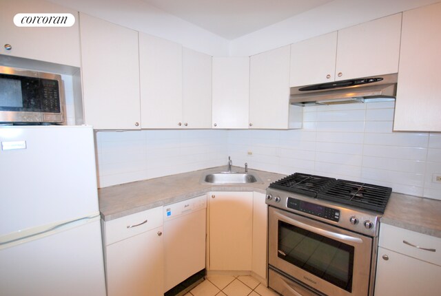 kitchen featuring white cabinetry, stainless steel appliances, sink, backsplash, and light tile patterned floors