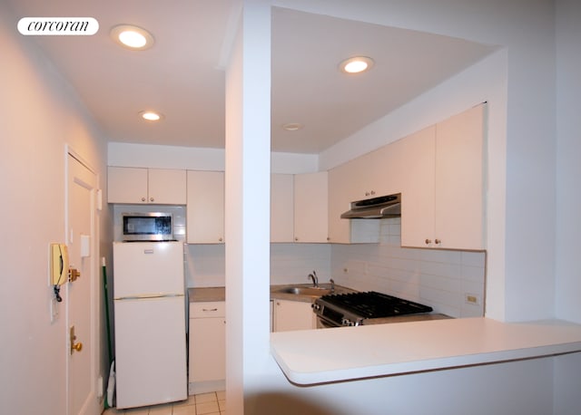 kitchen with kitchen peninsula, decorative backsplash, sink, stainless steel appliances, and light tile patterned floors