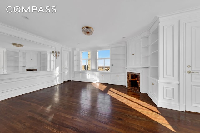 unfurnished living room featuring built in shelves, wood finished floors, and a high end fireplace