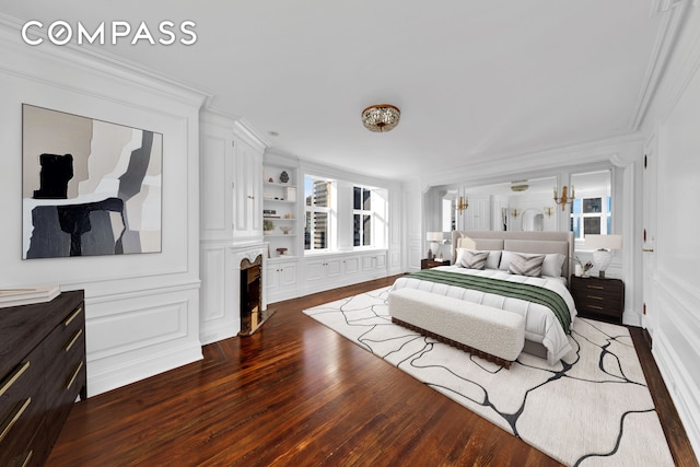 bedroom with a decorative wall, wood finished floors, and ornamental molding