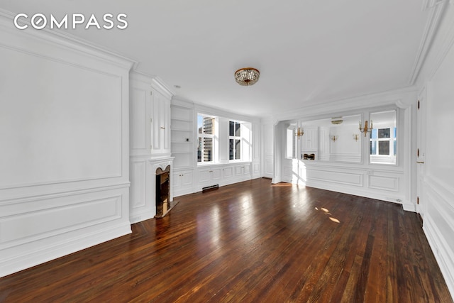 unfurnished living room with crown molding, a decorative wall, built in shelves, and a fireplace