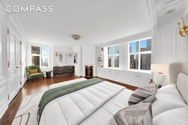 bedroom featuring dark wood finished floors, a decorative wall, and ornamental molding