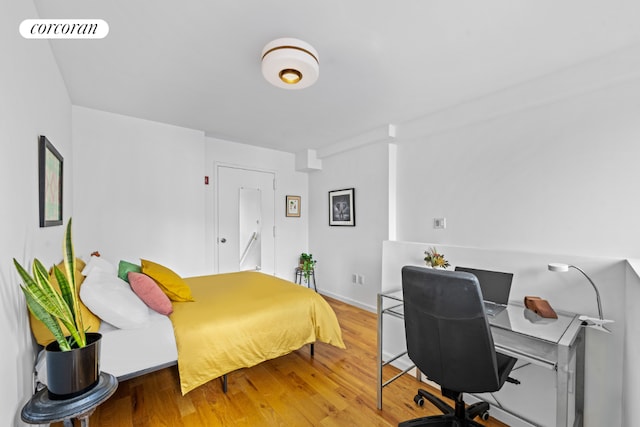 bedroom with baseboards, visible vents, and wood finished floors