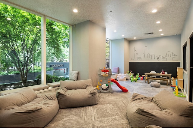 recreation room featuring a textured ceiling, recessed lighting, and a healthy amount of sunlight