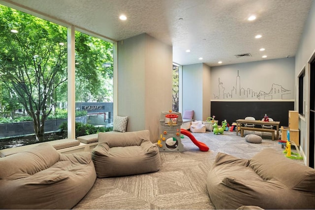 game room featuring a textured ceiling, recessed lighting, and a healthy amount of sunlight