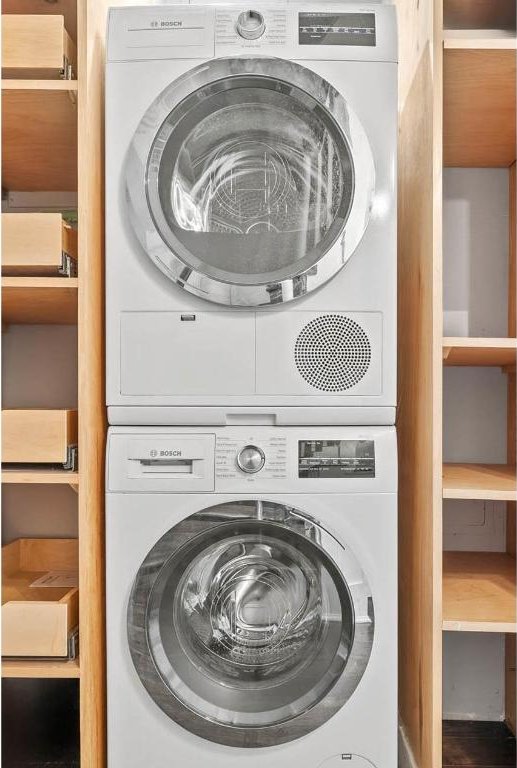 clothes washing area featuring stacked washer and dryer and laundry area