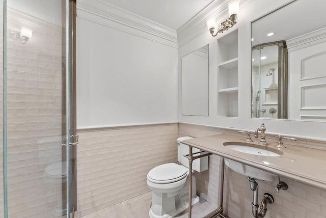 bathroom with a sink, a wainscoted wall, toilet, and crown molding