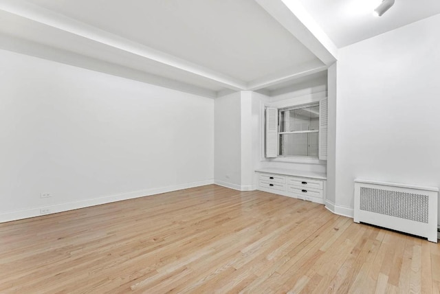 unfurnished room with light wood-type flooring, radiator heating unit, and baseboards