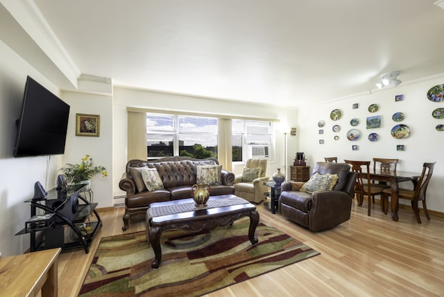 living room featuring light hardwood / wood-style floors, baseboard heating, and ornamental molding