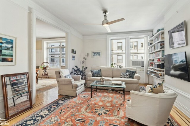 living room featuring ceiling fan, wood-type flooring, and crown molding