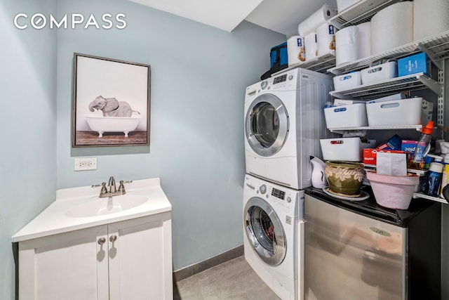 washroom featuring stacked washing maching and dryer, baseboards, laundry area, and a sink