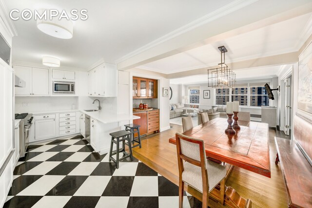 dining space with a notable chandelier, sink, and ornamental molding