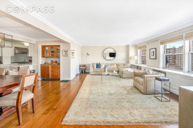 living area with ornamental molding and wood finished floors