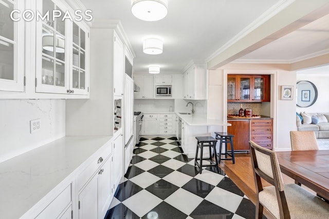444 E 84th St Phe, Phe, New York City, NY 10028 - kitchen featuring stainless steel microwave, white cabinets, backsplash, glass insert cabinets, and crown molding