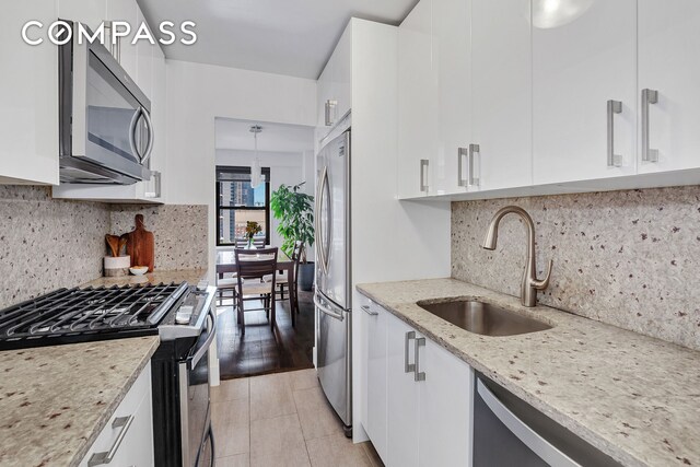 kitchen with appliances with stainless steel finishes, decorative backsplash, white cabinetry, and light stone counters