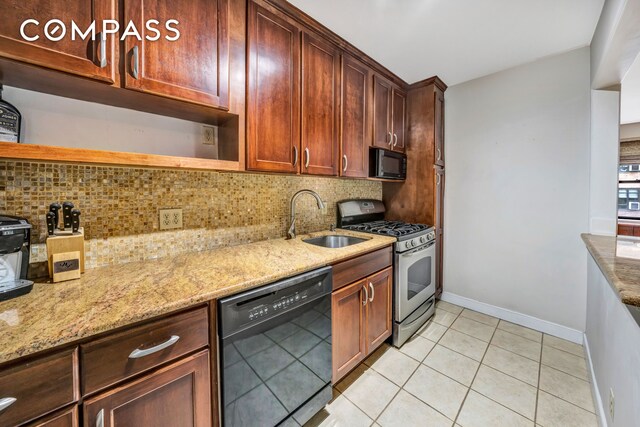 kitchen featuring black appliances, decorative backsplash, light stone countertops, and sink