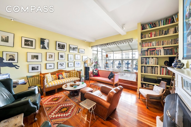 sitting room featuring beamed ceiling and wood finished floors