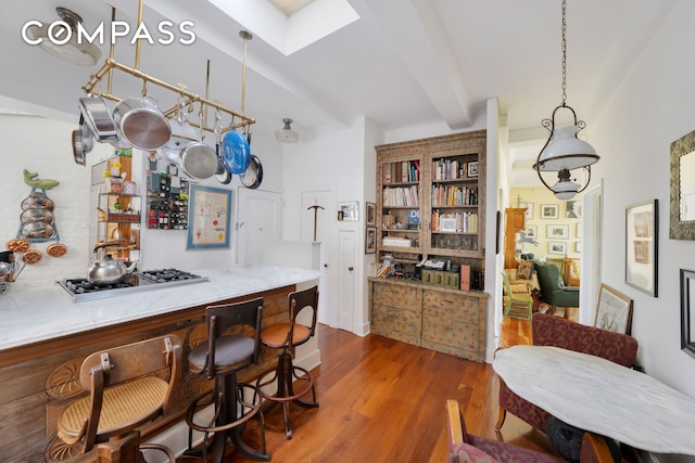 bar with a bar, gas stovetop, wood finished floors, and beam ceiling