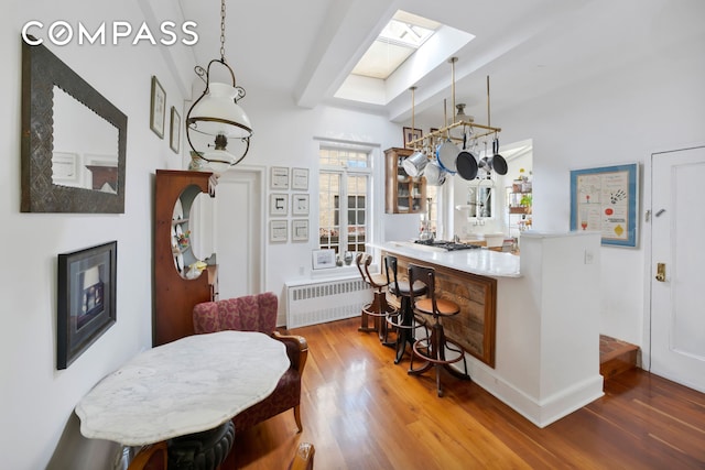 interior space with radiator heating unit, a kitchen bar, and wood finished floors