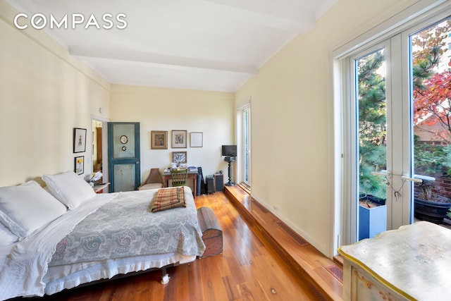 bedroom featuring access to outside, beamed ceiling, baseboards, and wood finished floors