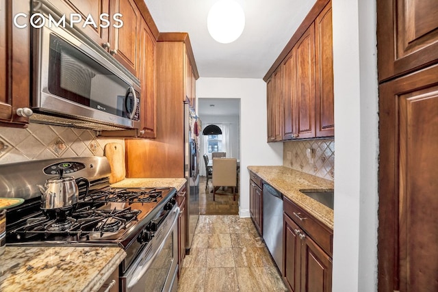 kitchen with light stone countertops, appliances with stainless steel finishes, sink, and backsplash