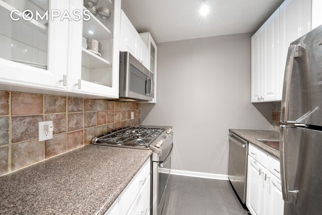 kitchen featuring stainless steel appliances, white cabinetry, and decorative backsplash