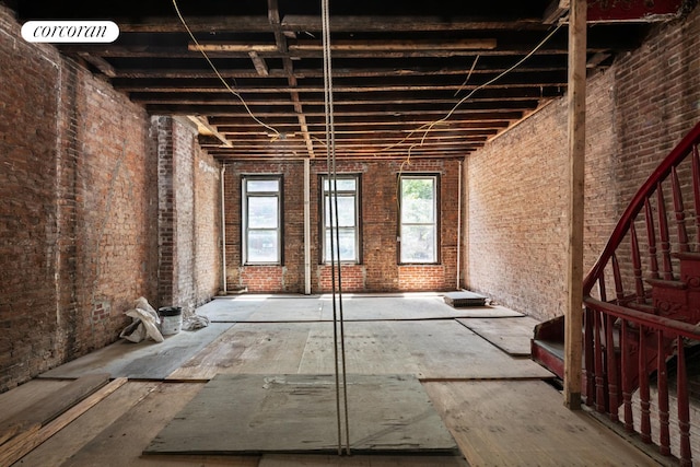 miscellaneous room featuring a towering ceiling, brick wall, and visible vents