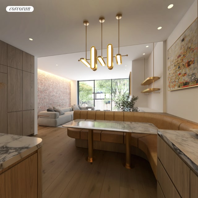 kitchen with brick wall, light hardwood / wood-style floors, and hanging light fixtures