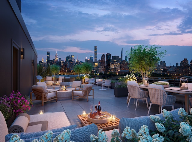 patio terrace at dusk featuring a view of city and an outdoor living space with a fire pit