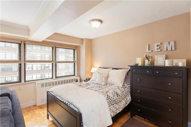 bedroom with radiator, ornamental molding, and light parquet flooring