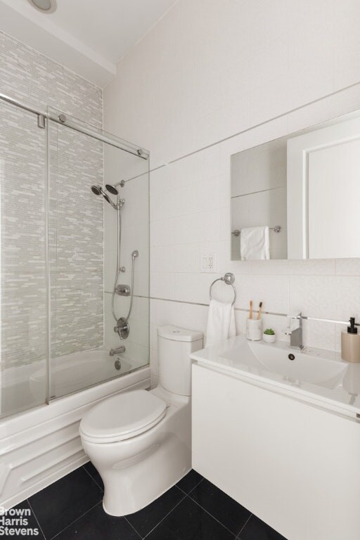 full bathroom with enclosed tub / shower combo, tile walls, backsplash, toilet, and vanity