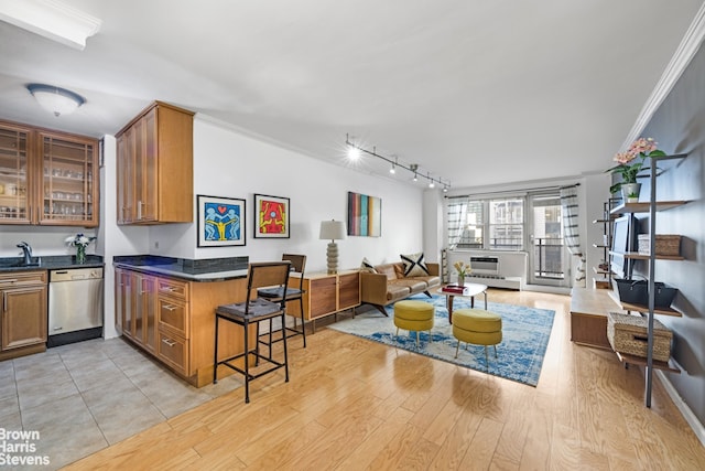 kitchen featuring crown molding, dishwasher, sink, light hardwood / wood-style floors, and a breakfast bar area