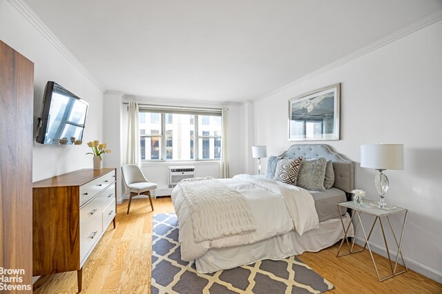 bedroom featuring light wood-type flooring, an AC wall unit, and crown molding