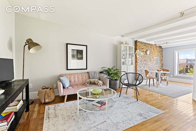 living room with baseboards, beam ceiling, wood finished floors, and a fireplace