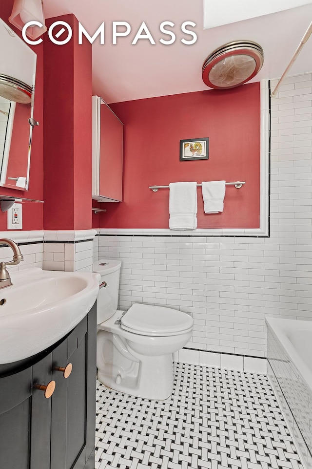 bathroom featuring tile patterned floors, a wainscoted wall, toilet, and tile walls