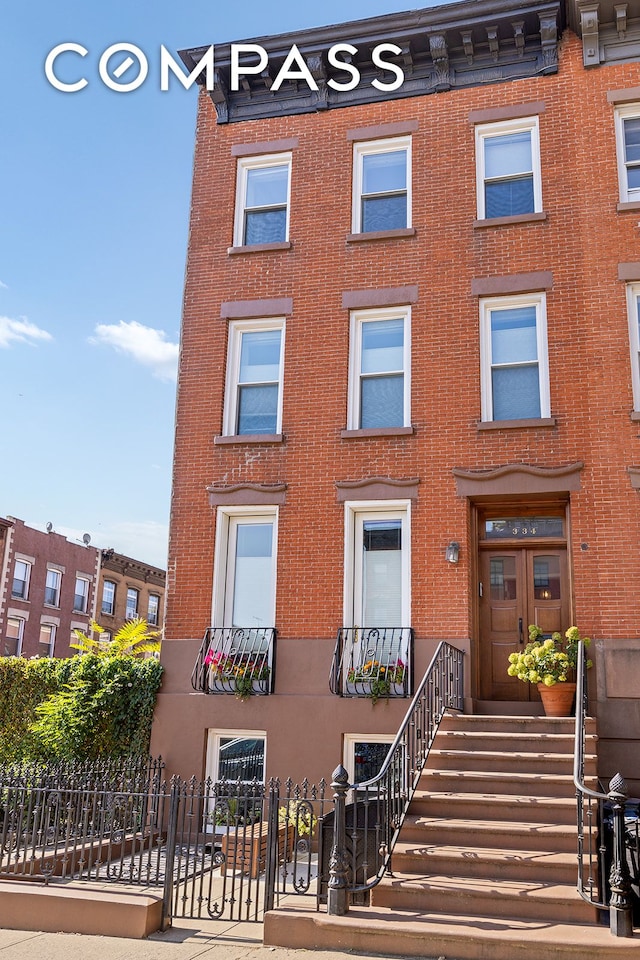 multi unit property with a fenced front yard and brick siding