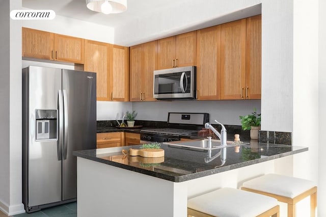 kitchen with a peninsula, appliances with stainless steel finishes, dark stone countertops, and visible vents