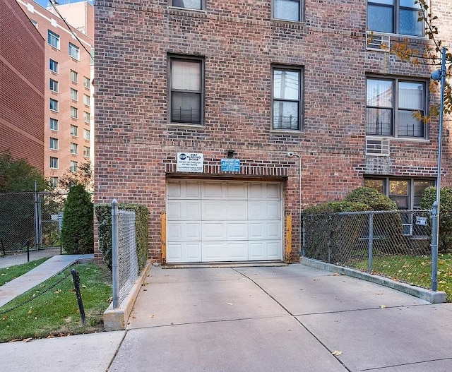 garage featuring concrete driveway and fence