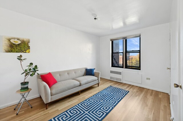 living area with radiator heating unit, wood finished floors, and baseboards