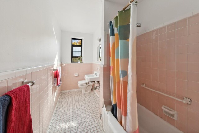 full bath with tile walls, wainscoting, toilet, tile patterned floors, and shower / bath combination with curtain