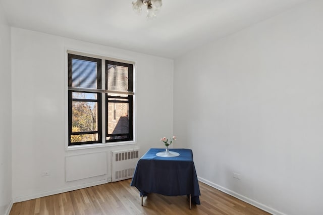 unfurnished room featuring radiator heating unit, baseboards, and wood finished floors